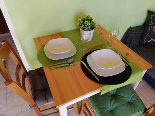 a dining room table with two white plates and glasses at Panoramic view studio in Rab
