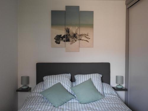 Un dormitorio con una cama con tres cuadros en la pared. en Résidence Casino, en Andernos-les-Bains