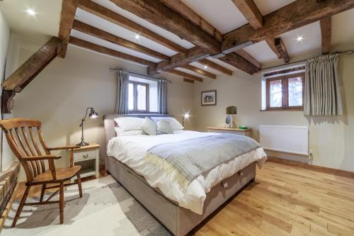 a bedroom with a large bed and a chair at The Stables and Hayloft in Ledbury