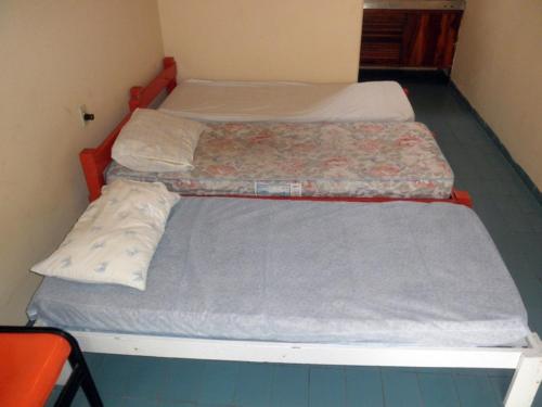 two beds in a small room with blue floor at Kit's Ubatuba in Ubatuba