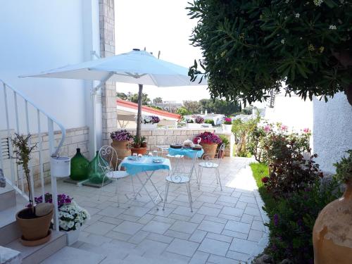een terras met tafels, stoelen en een parasol bij Vento d'aMare in Leporano