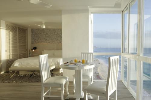 a bedroom with a bed and a table and chairs at Oleo Cancun Playa All Inclusive Resort in Cancún