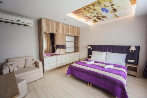 una camera da letto con un grande letto viola e un divano di Levendula Apartmanház a Sárvár