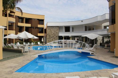 a pool at a hotel with a bridge and chairs and umbrellas at Embassy Beach in Pisco