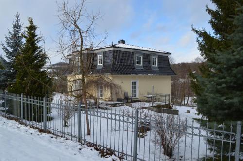 a house behind a fence in the snow at Ferienwohnung Lucia in Bad Schlema
