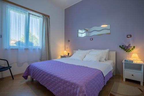 a bedroom with a large bed with a purple blanket at Apartment Green Garden in Pula