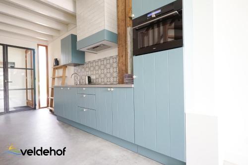 a kitchen with blue cabinets and a stove at 't Veldehof in Domburg
