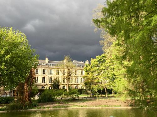 a building in a park with a lake and trees at Romance au coeur de Bordeaux / Jardin Public in Bordeaux
