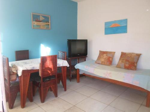 Habitación con mesa, TV, mesa y sillas. en Casa de praia, en Salvador