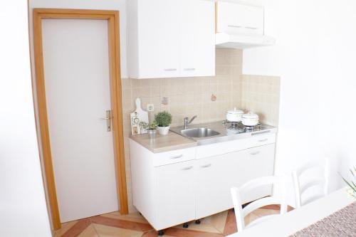 a white kitchen with a sink and a counter at Apartmani Adrijan Krk in Krk