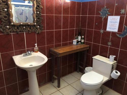 a bathroom with a toilet and a sink and a mirror at Luminosa Montezuma Hostel in Montezuma