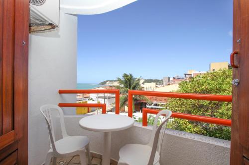a balcony with a table and chairs and the ocean at Marambaia Apart Hotel in Natal