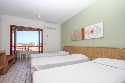 Habitación con 4 camas y balcón. en Marambaia Apart Hotel, en Natal