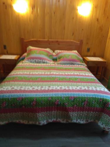Una cama con una manta de colores encima. en nancy, en Pucón