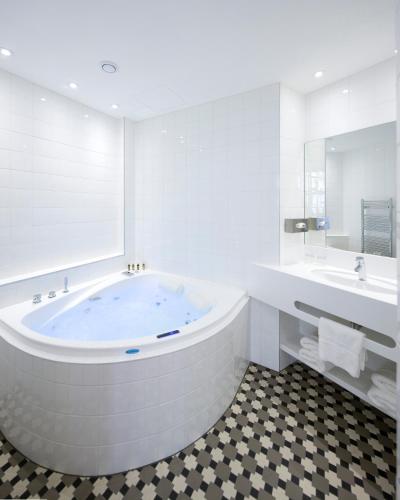 a large white bathroom with a tub and two sinks at HANNONG Hotel & Wine Bar in Strasbourg