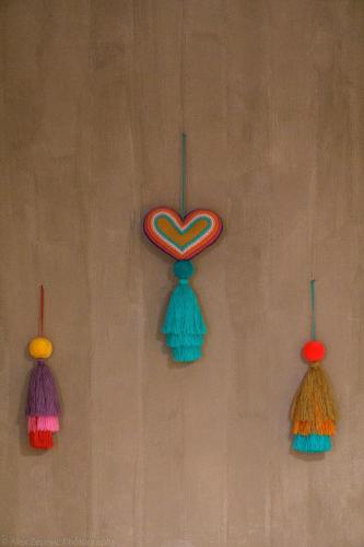 four tassels on a wall with a heart on it at La Abuelita Hostal in San Cristóbal de Las Casas