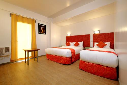 a hotel room with two beds and a window at Frankfurter Deluxe Inn in Cebu City