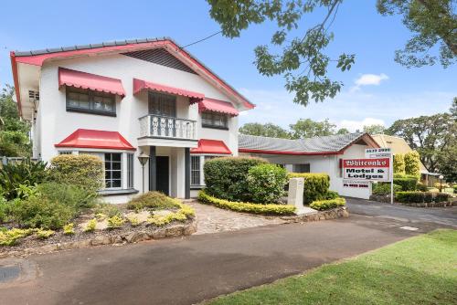 a white house with red awnings on a street at Whiteoaks Motel & Lodges in Toowoomba