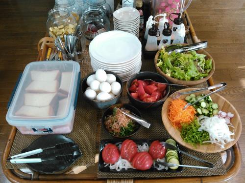 a table topped with bowls of vegetables and other foods at Pension Megumiyuki in Biei