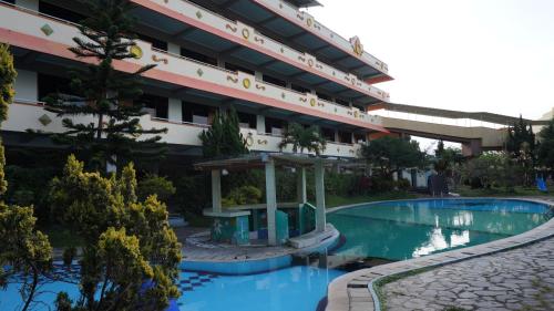 un hotel con piscina di fronte a un edificio di Hotel Surya Indah Batu Malang a Batu