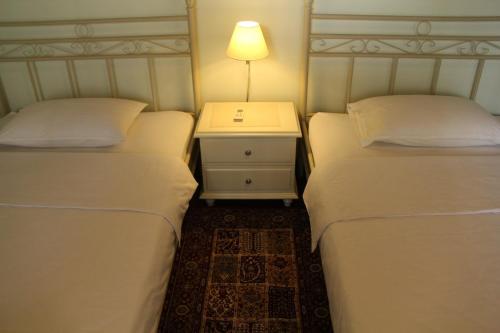 two beds in a room with a nightstand between them at Bed and Breakfast Tomang in Jakarta