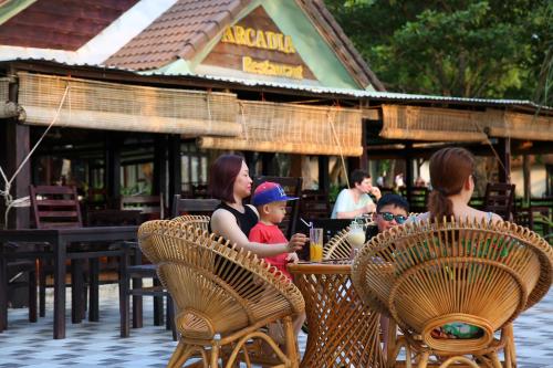 a woman and children sitting at a table at a restaurant at Arcadia Phu Quoc Resort in Phú Quốc