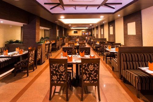 a restaurant with tables and chairs in a room at Clinton Park Inn in Velankanni