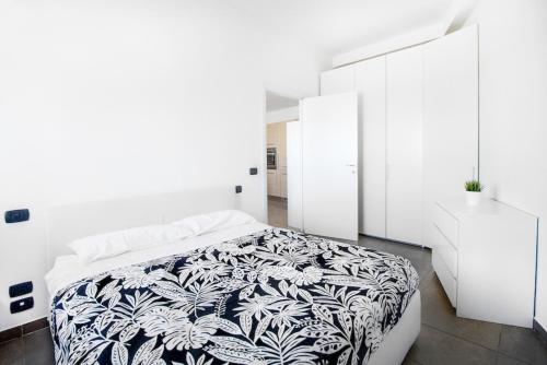 a white bedroom with a bed with a black and white blanket at Orange Apartment Bologna in Bologna