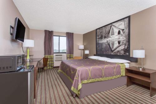 een hotelkamer met een bed en een televisie bij Super 8 by Wyndham Columbus Airport in Columbus