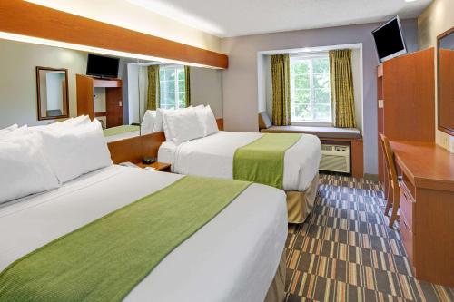 a hotel room with two beds and a desk at Microtel Inn & Suites by Wyndham Cherokee in Cherokee