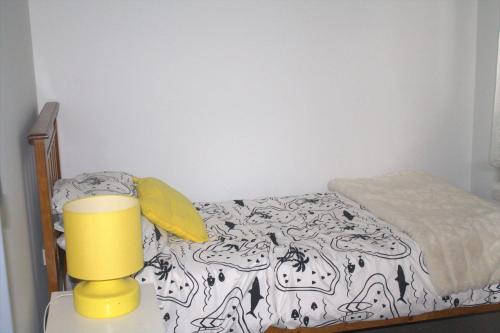 Dormitorio pequeño con cama y lámpara amarilla en Ducati's B and B, en Raymond Terrace