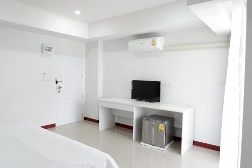 a white bedroom with a desk with a tv on it at Phimai Residence in Phimai