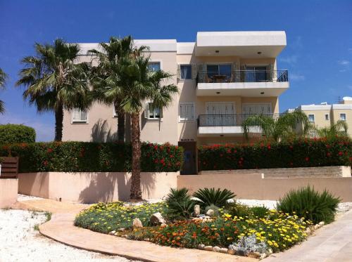 a large white building with palm trees and flowers at Sunny Garden Limassol Star in Limassol