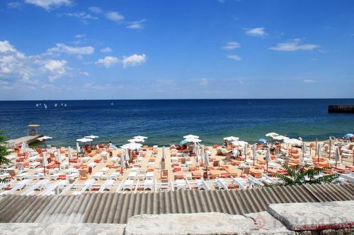 a beach with chairs and umbrellas and the ocean at Гостевой Дом у Моря, Guest House by the Sea in Odesa