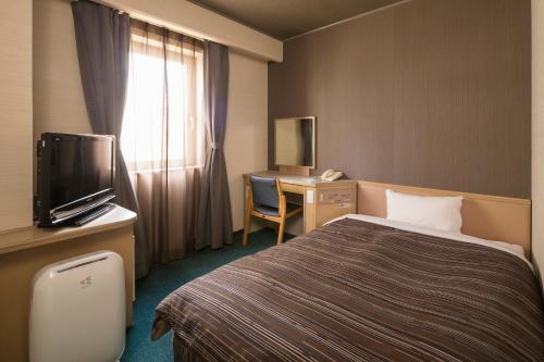 um quarto de hotel com uma cama e uma secretária com uma televisão em Ark Hotel Okayama -ROUTE INN HOTELS- em Okayama