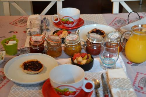 a table topped with plates of food and jars of jam at La Maison aux Hortensias in Verneuil-en-Bourbonnais