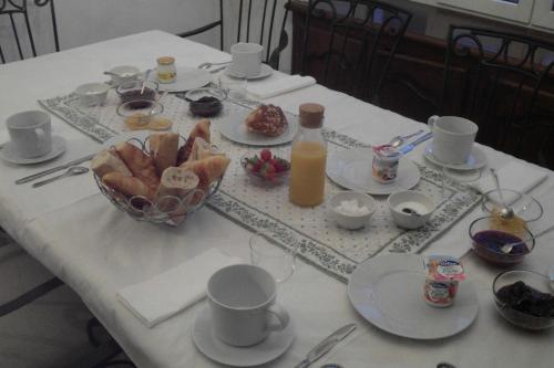 - une table blanche avec des assiettes de nourriture et une bouteille de jus d'orange dans l'établissement Chambres d'hôtes Gela Itsasoa Océan, à Ciboure