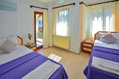1 dormitorio con 2 camas, sábanas moradas y ventanas en Villa Beste en Dalyan