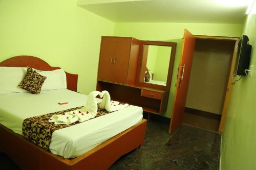 a bedroom with a bed with two swans on it at Hotel Vijay in Pollāchi