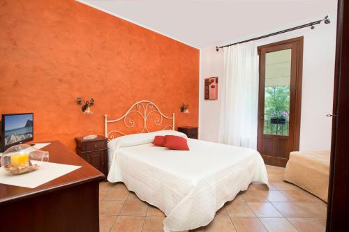 a bedroom with a white bed and an orange wall at Cala di Ponente in Castelluzzo