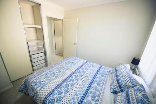 a bedroom with a blue and white bed and a mirror at Midland Haven - Midland WA in Midland Junction