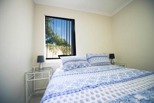 a bedroom with a blue and white bed and a window at Midland Haven - Midland WA in Midland Junction
