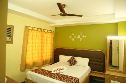 a bedroom with a bed and a ceiling fan at Hotel Vijay in Pollāchi
