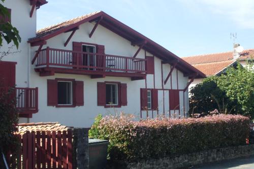 Casa blanca con balcones rojos y valla en Chambres d'hôtes GELA ITSASOA Baie, en Ciboure