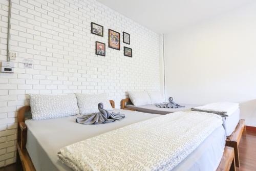 Duas camas num quarto com paredes de tijolos brancos em The Garage em Chiang Rai