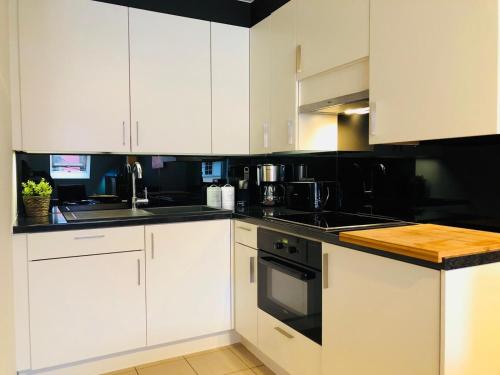 a kitchen with white cabinets and black counter tops at Duintje-Vosseslag De haan in De Haan