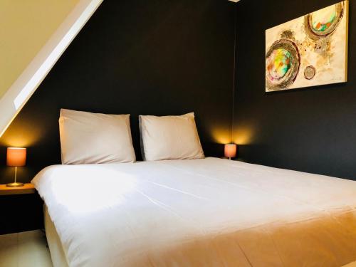 a bedroom with a large white bed with two lamps at Duintje-Vosseslag De haan in De Haan