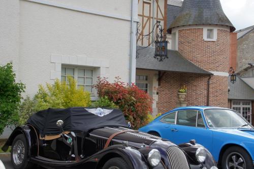 a car and a motorcycle parked in front of a house at Relais des Trois Châteaux in Cour-Cheverny