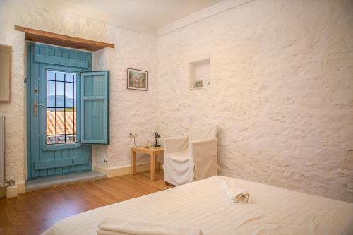 1 dormitorio con cama, puerta azul y mesa en Villa Smaragda en Limeni