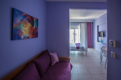 a living room with a purple couch and a painting on the wall at Sea to See in Néa Péramos